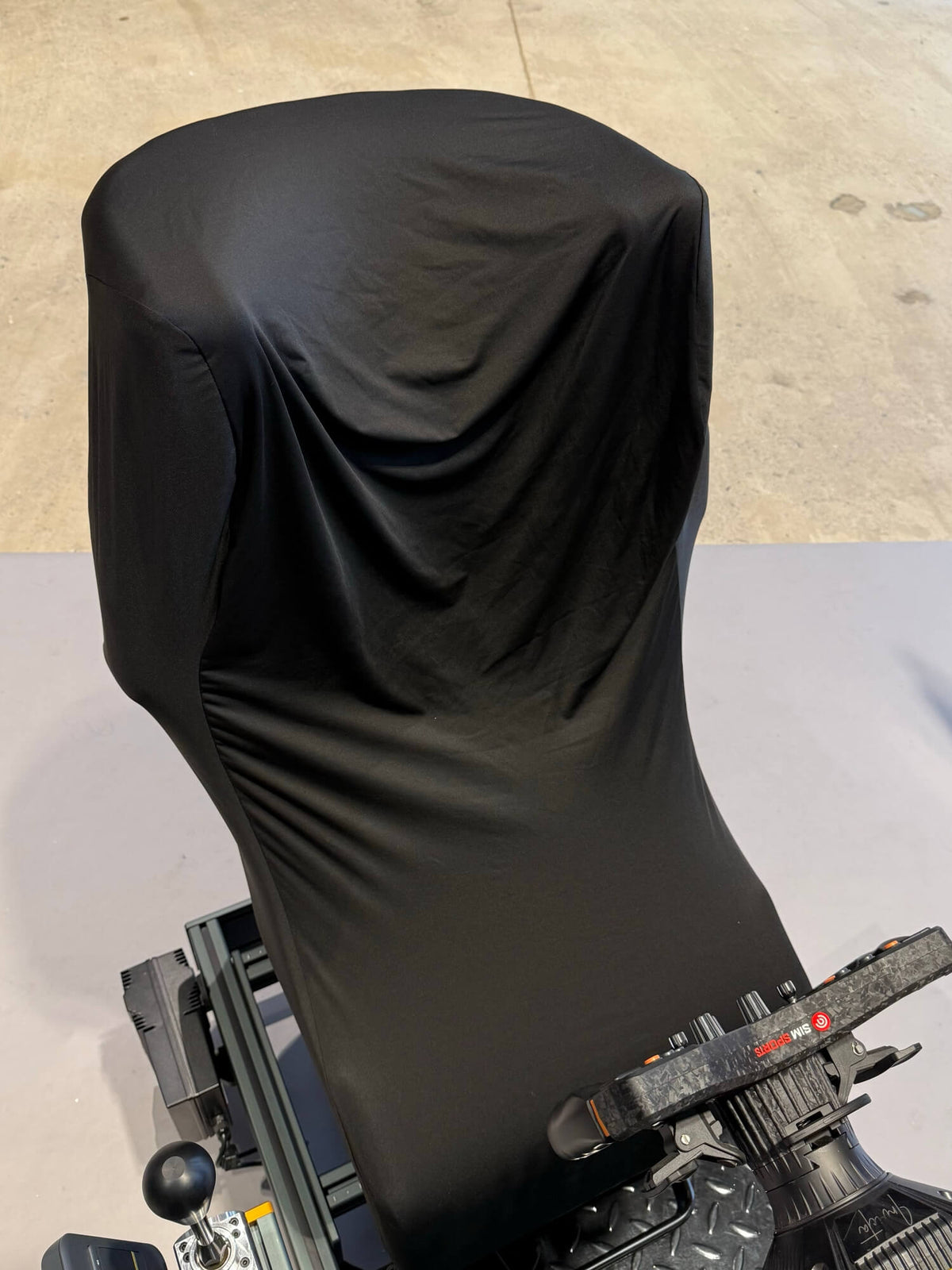 Black stretch cover over a SPEC 282 rig and seat, front view with triple monitors