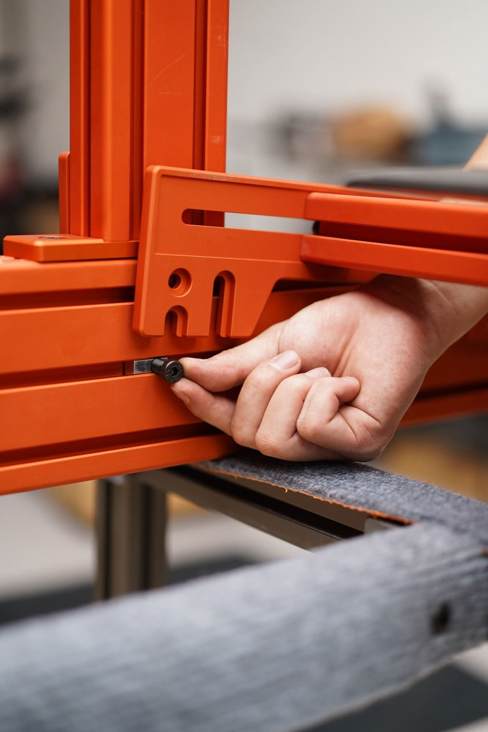 A hand tightening a bolt on an orange SPEC 282 bracket