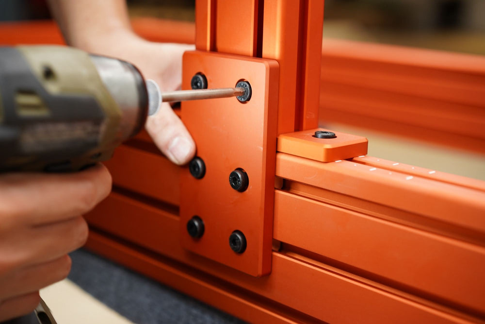 A cordless driver fastening a plate to an orange SPEC 282 upright