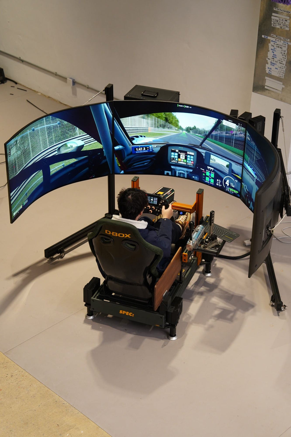 A driver in a D-BOX motion rig on a SPEC base, three curved screens showing a race