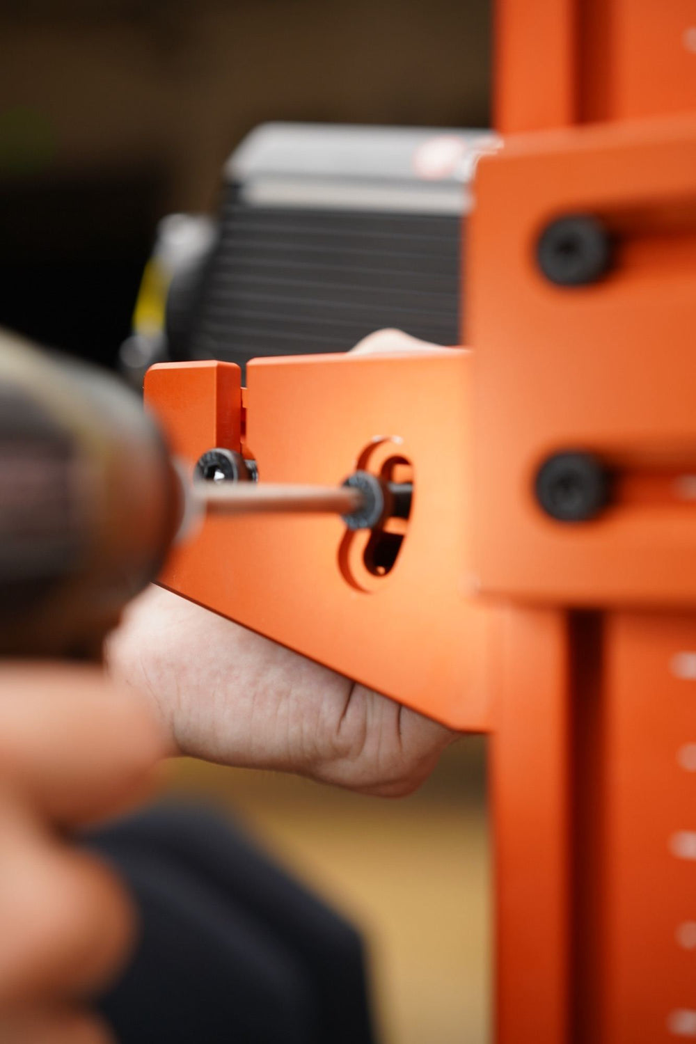 A cordless driver fastening a bracket to an orange SPEC 282